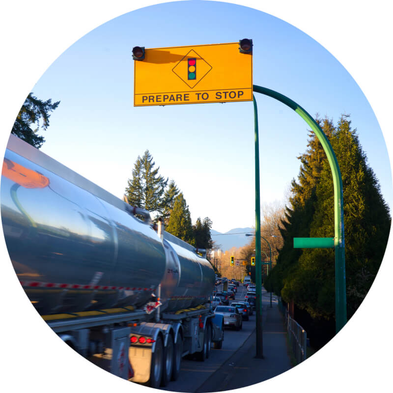 Image of conventional tanker truck on road. Above truck is a 'Prepare to Stop' sign.